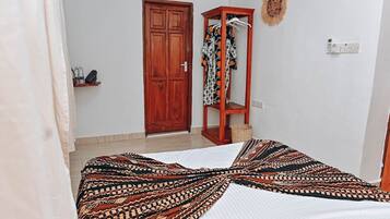 A bedroom with a bed, a wardrobe, a mirror, and a wall-mounted heater.