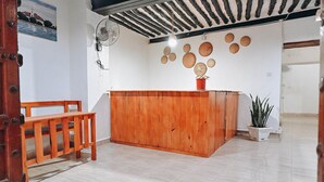A reception area with a wooden desk, a bench, and a fan.