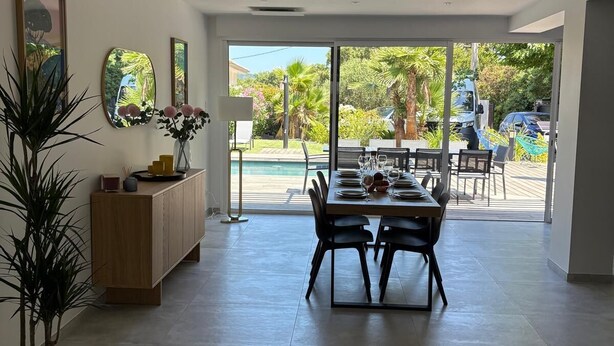 A spacious room with a dining area, a wooden cabinet, and a large window offering a view of the outdoors. - Family villa with a pool, 100 meters from the beach – Le Lavandou (Le Lavandou)