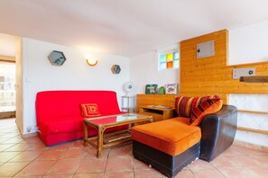 Ein Wohnzimmer mit einem roten Sofa, einem schwarzen Sofa, einem Glastisch und einem Holzschrank.
