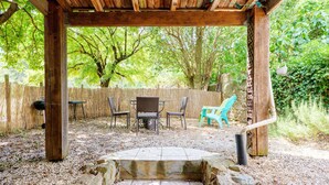 Un espace extérieur aménagé en patio, doté d’une pergola, d’un barbecue et d’un coin salon comprenant des chaises et une table.
