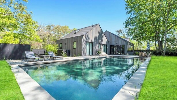 Una casa moderna con piscina, patio coperto e prato curato.