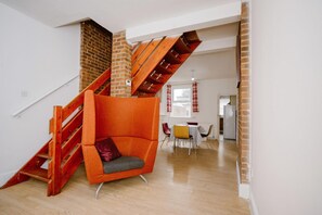 A modern interior with a wooden staircase, a red chair, and a dining area. - Feels like home (Ilkeston)