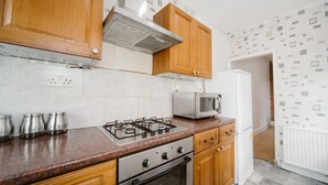 A kitchen with wooden cabinets, a gas stove, a microwave, and a refrigerator.