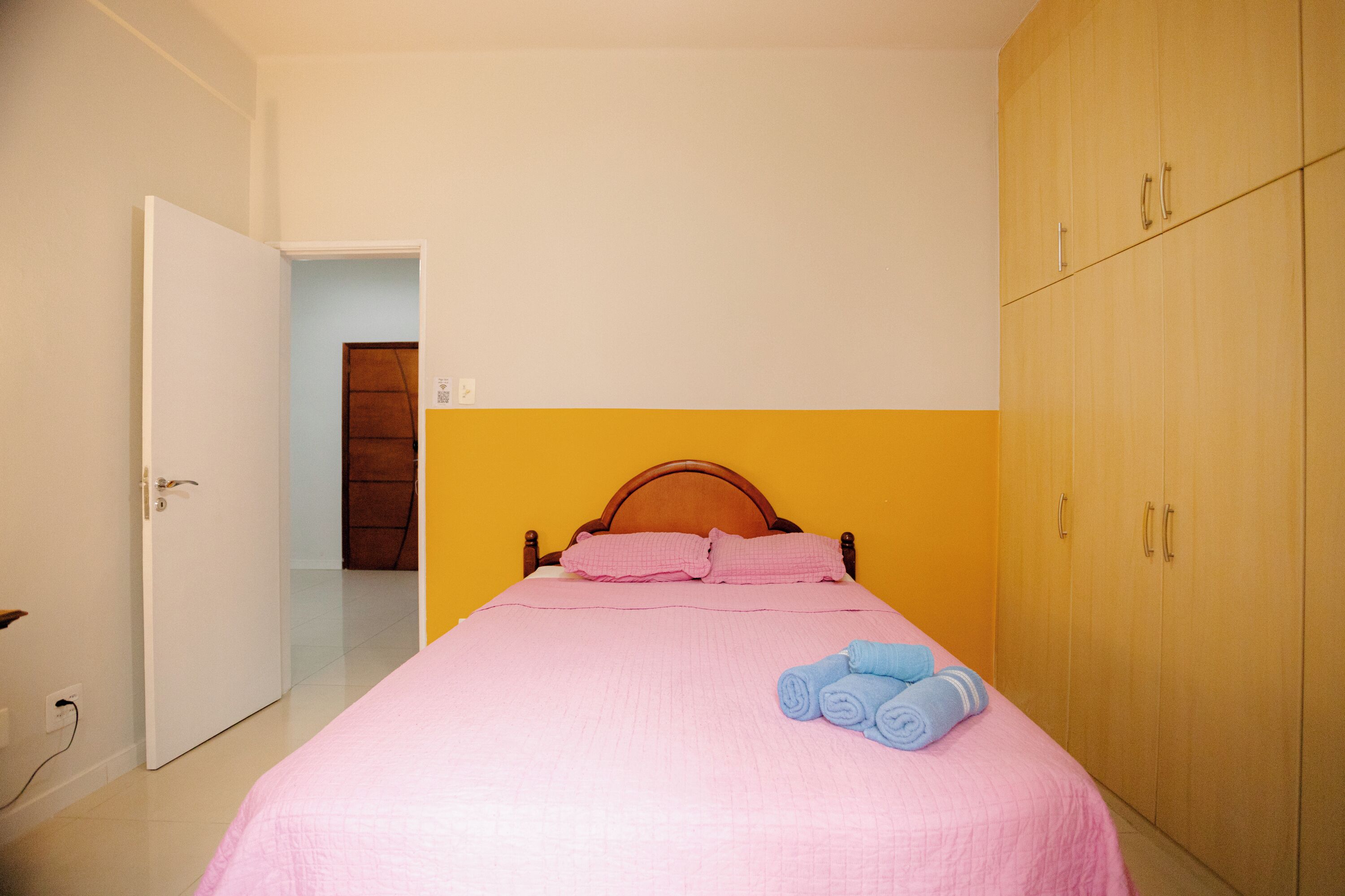 A bedroom with a bed, a wardrobe, and a door leading to another room.