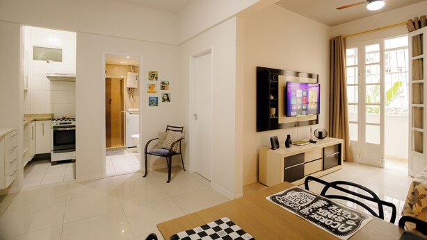 Una sala de estar moderna con comedor, cocina y televisor montado en la pared.