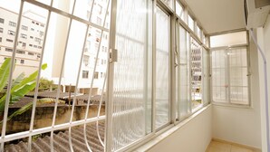 Una habitación con ventanas amplias, suelo de baldosas y un balcón visible con barandilla.