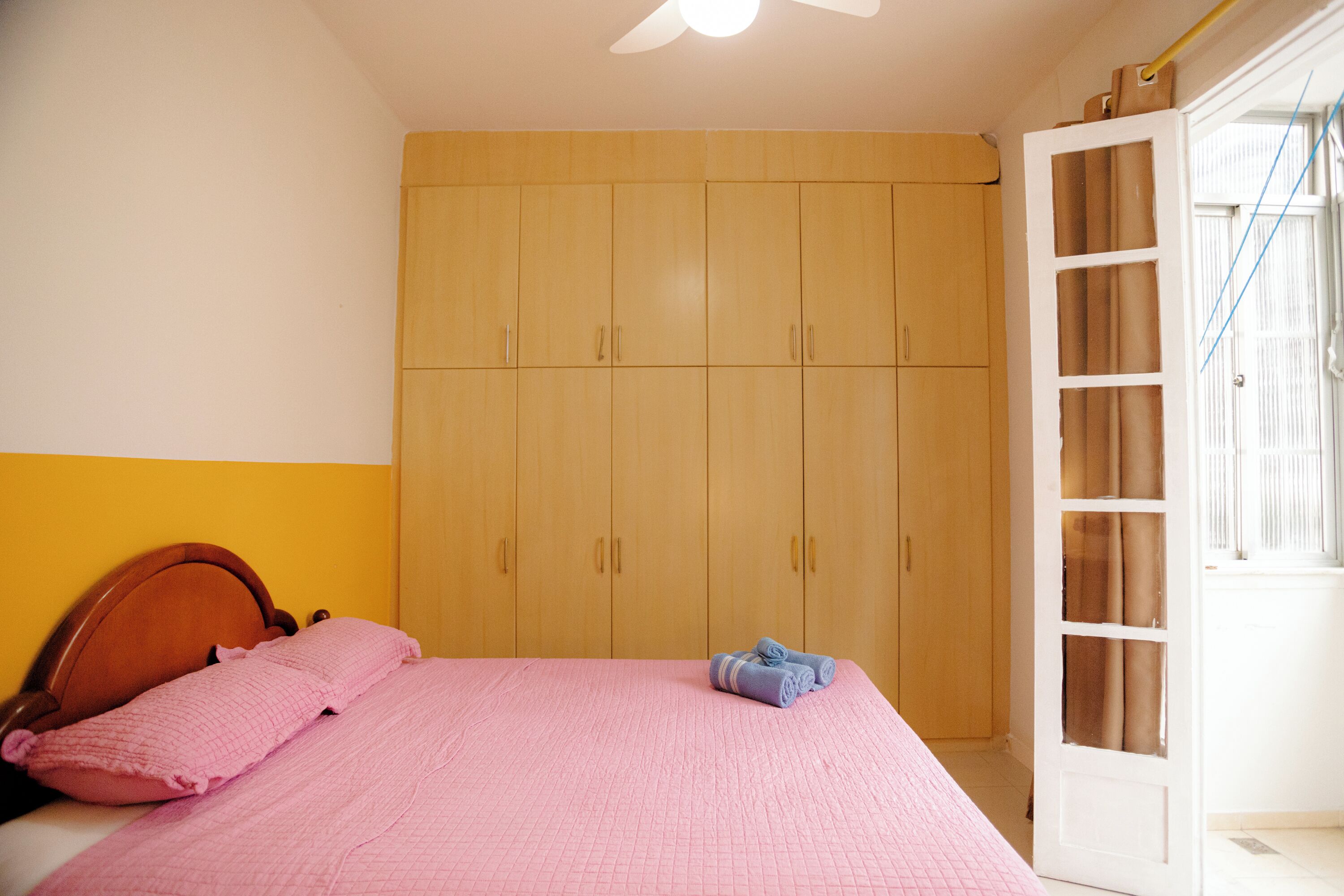 Ein Schlafzimmer mit einem Bett, einem Holzschrank und einer Tür mit Fenster.