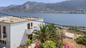 A modern building with a flat roof, large windows, and a balcony overlooking a body of water and mountains.
