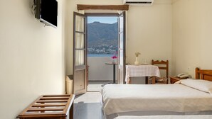 Ein Hotelzimmer mit zwei Betten, einem Fernseher, einem Tisch mit Stuhl und einem Balkon mit Bergblick.