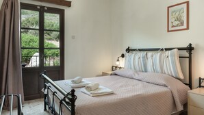 A bedroom with a bed, a window with curtains, a bedside table, and a wall-mounted picture.