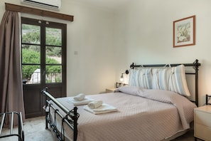 A bedroom with a bed, a window with curtains, a bedside table, and a wall-mounted picture.
