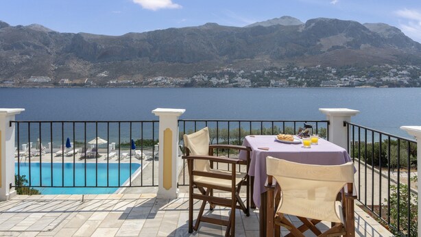 Una terraza con mesa y sillas que da a una piscina y un paisaje montañoso.