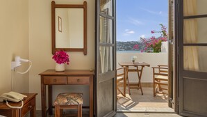 Una habitación con escritorio, silla y vistas a un balcón lleno de flores.