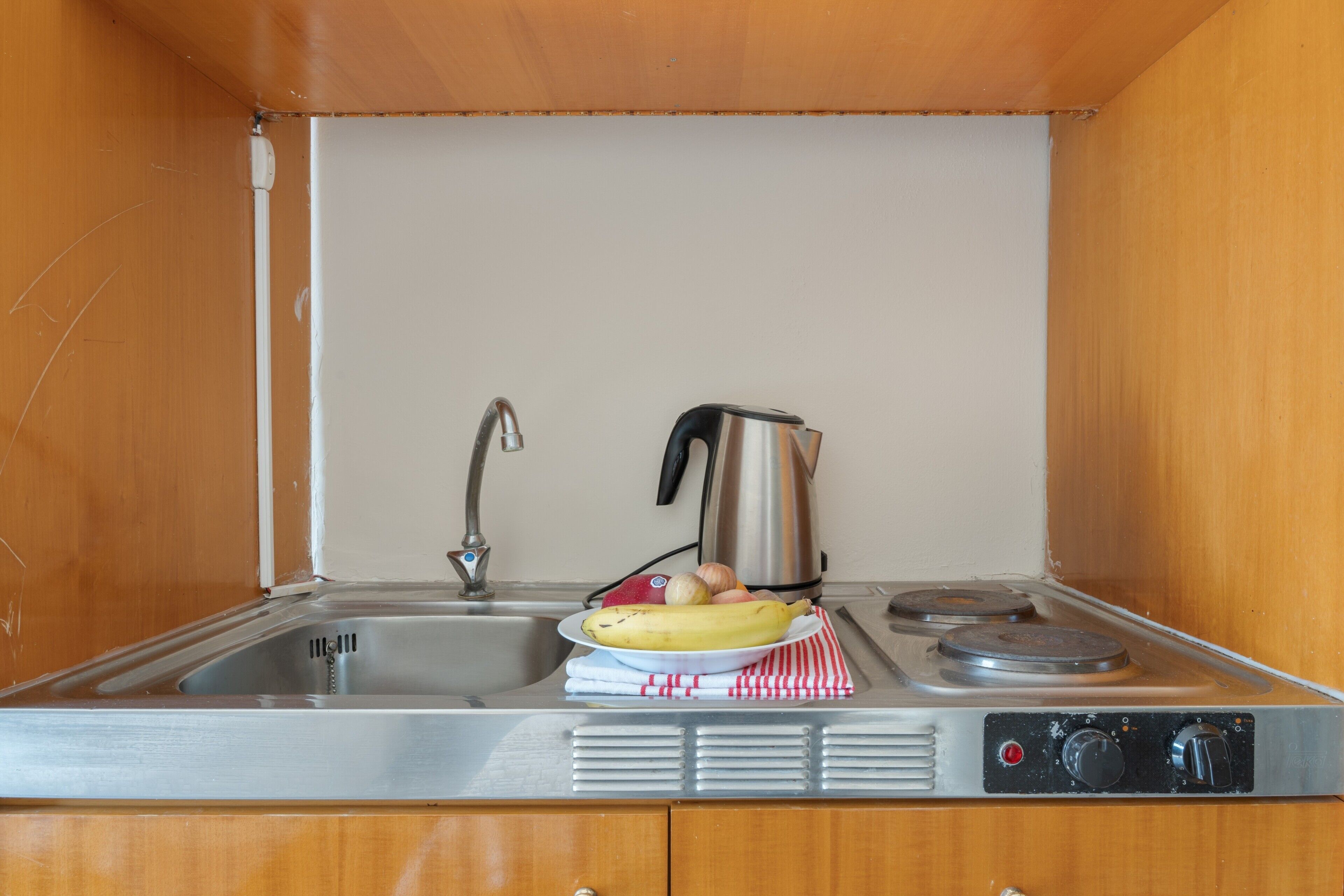 Une petite cuisine équipée d’un évier, d’une cuisinière et d’une casserole.
