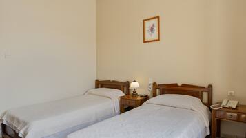 Une chambre avec deux lits simples, des tables de chevet, une lampe, un téléphone et un tableau encadré au mur.