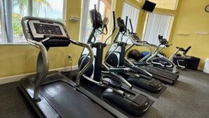 Une salle de sport équipée de tapis de course, de vélos d’exercice et d’un vélo stationnaire.
