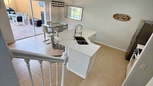 Une cuisine moderne dotée d’un îlot central, d’un coin repas avec des chaises et d’un escalier menant à un autre niveau.