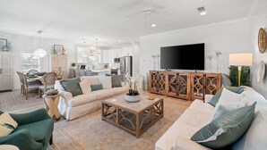 Ein geräumiges Wohnzimmer mit einem großen Fernseher, einem Holztisch und einem Sofa.