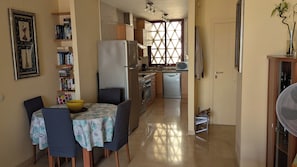 A compact kitchen with a refrigerator, oven, and microwave. There is a dining table with chairs and a yellow bowl. - Casares Costa, Vista Bahia,2 Bedroom Bathroom (Casares)