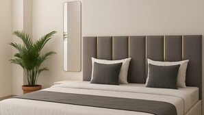 Ein modernes Schlafzimmer mit einem großen Bett, einer Topfpflanze und einem wandmontierten Spiegel.