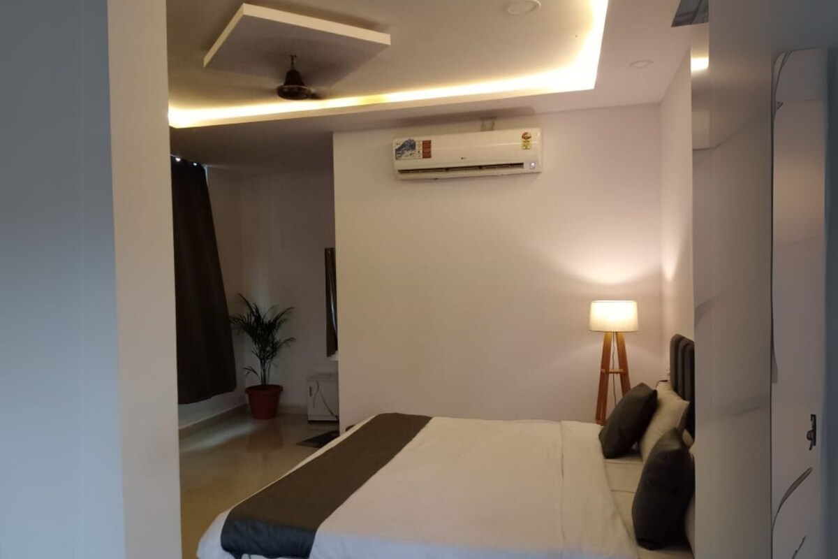 A modern bedroom with a marble bed, a standing lamp, and an air conditioning unit on the wall.