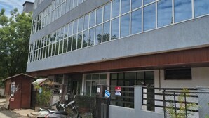 Ein modernes Gebäude mit vielen Fenstern, einem verschlossenen Eingang und einem abgestellten Roller.