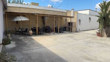 An outdoor patio area with a brick wall, a wooden pergola, and a pizza oven.