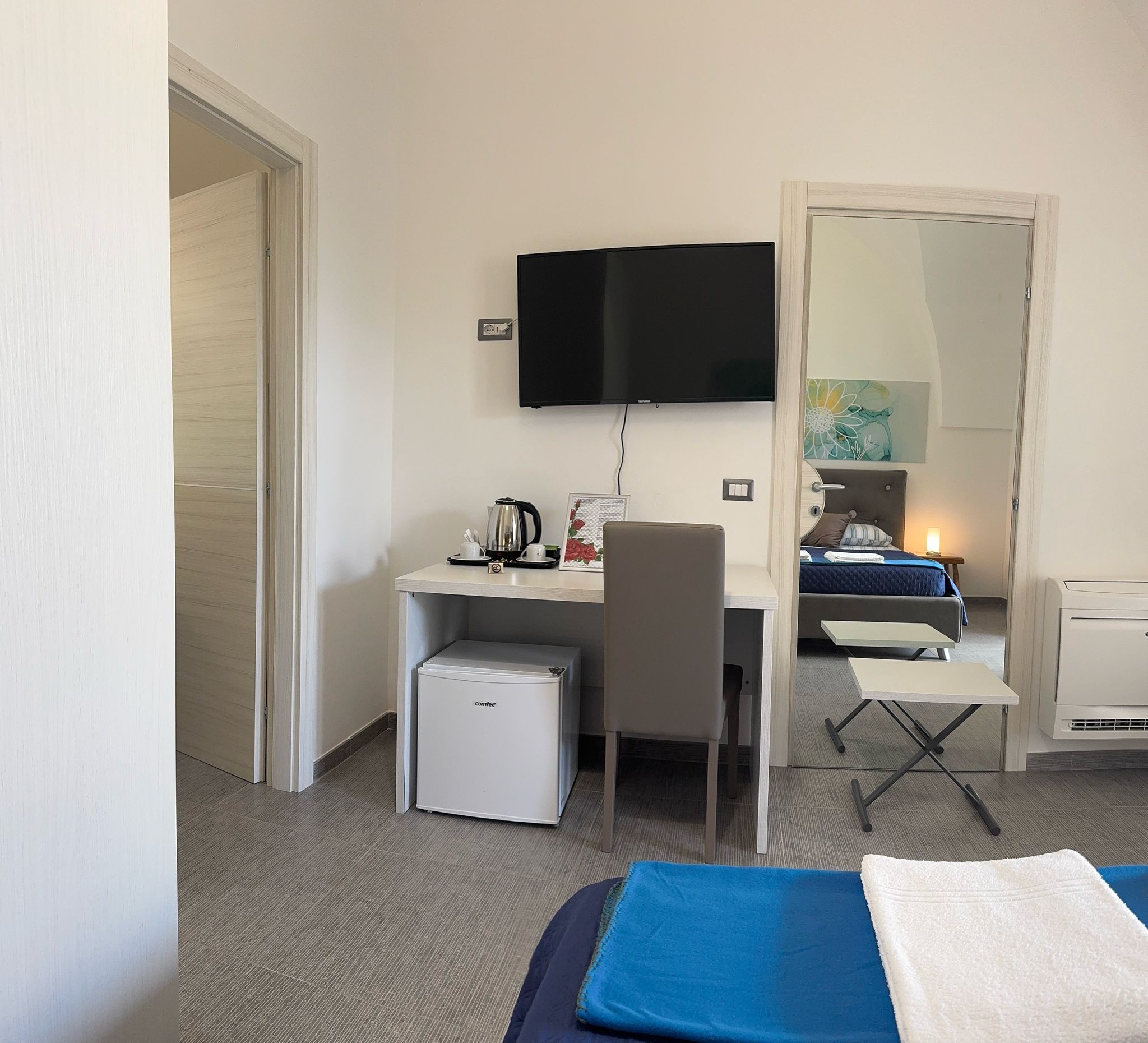 Une chambre d’hôtel équipée d’un bureau, d’une chaise, d’un lit et d’un petit réfrigérateur.