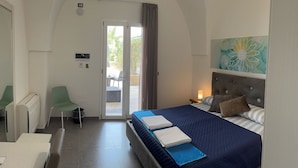 A hotel room with a bed, a chair, a table, and a door leading to a balcony. - Dear Mary B&B (San Cesario di Lecce)