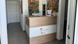 A reception desk with a 'Dear Mary' sign, two colorful floral paintings, and a potted plant. - Dear Mary B&B (San Cesario di Lecce)