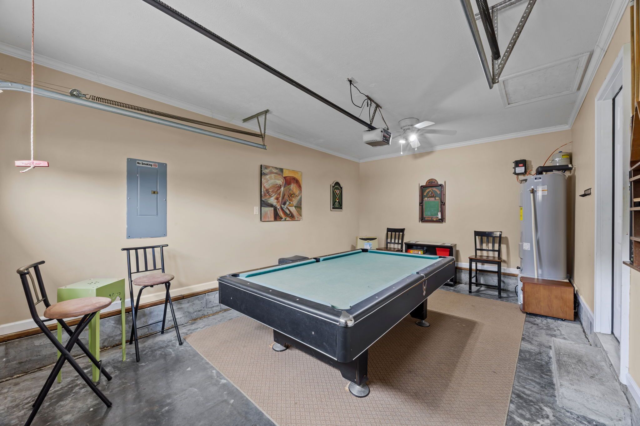 A pool table in a room with a ceiling fan, a 'No Smoking' sign, and a water heater.