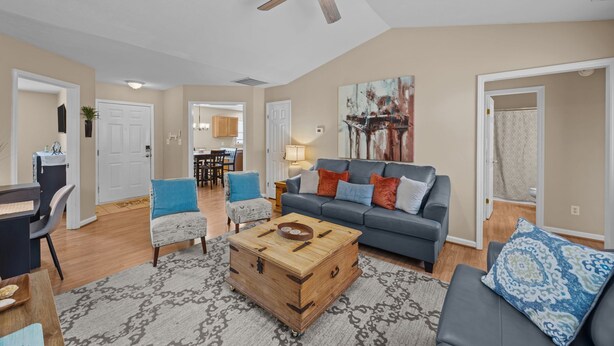 A spacious living room with a grey sofa, a wooden coffee table, and a ceiling fan. - 3-Bedroom Retreat with King Suite, Pool Table & Private Fenced Yard (New Bern)