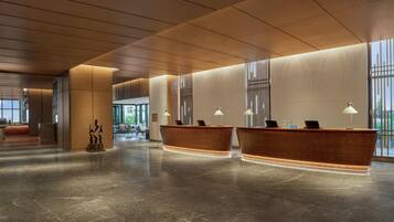 A spacious lobby with two reception desks, a modern ceiling design, and large windows.