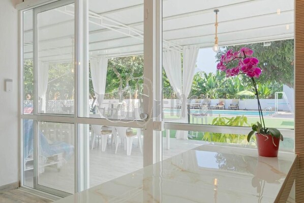 A modern room with large glass doors leading to an outdoor area with a pool and lounge chairs.