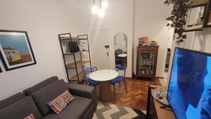 A living room with a sofa, a dining table with chairs, a TV, and a mirror. - 360 Flamengo Marques de Abrantes By SUHCasa (Rio de Janeiro)