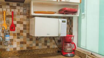 Uma cozinha com micro-ondas, cafeteira e painel de parede xadrez.