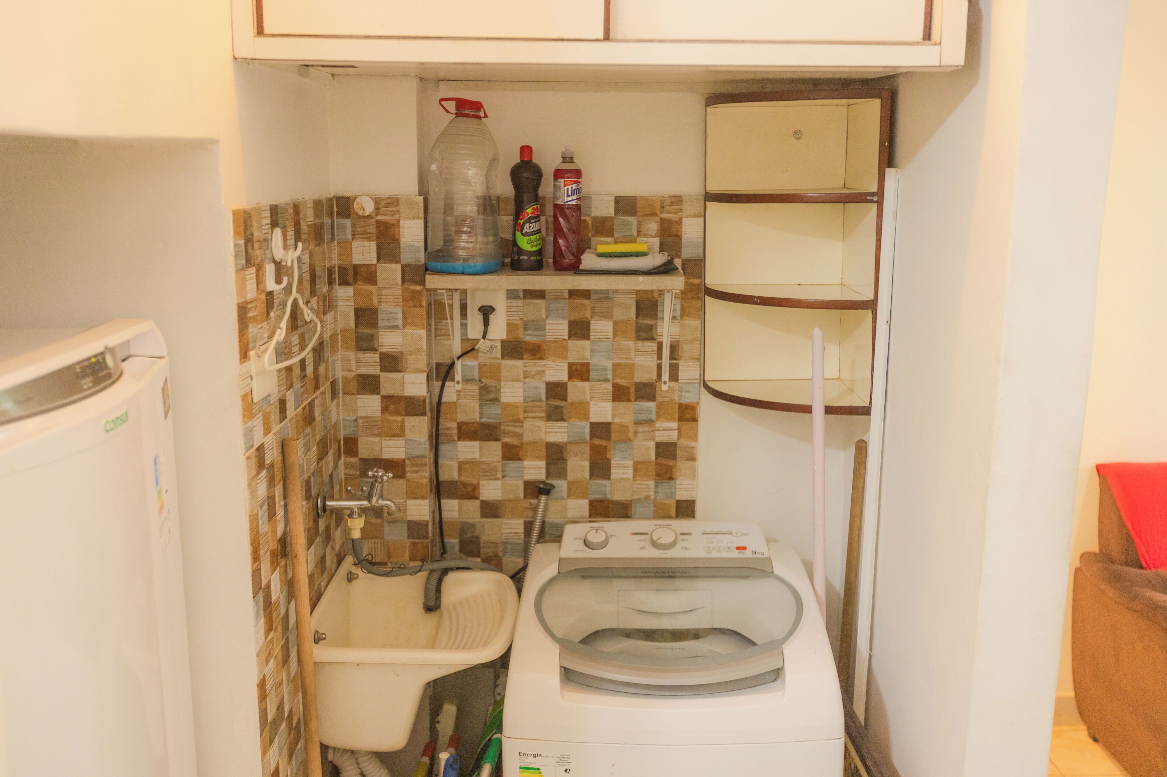A compact kitchen with a washing machine, a sink, and a tiled backsplash.