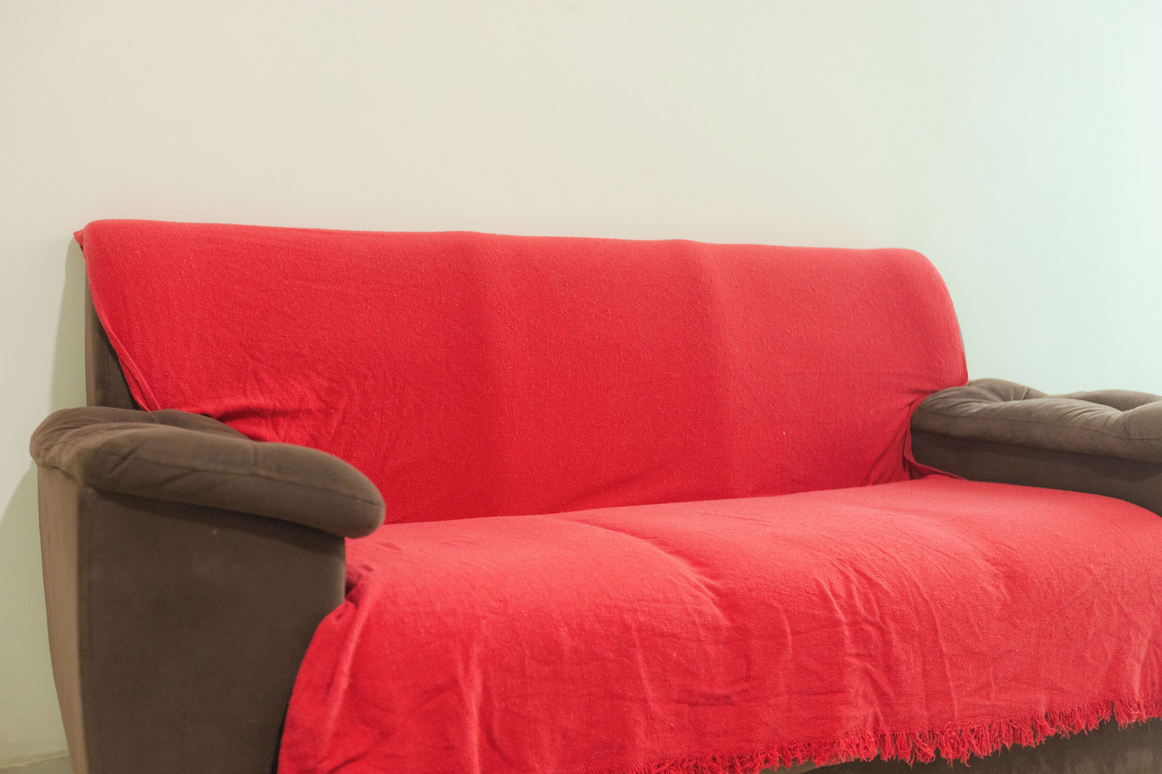 A brown sofa with a red blanket.