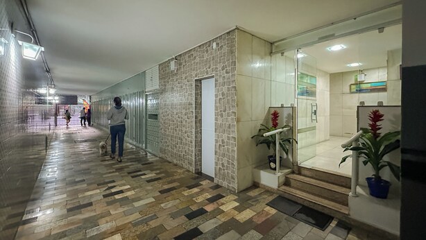 A hallway with patterned flooring, a stone wall, and a glass door leading to a room with a plant and a small staircase. - 360 Flamengo Marques de Abrantes By SUHCasa (Rio de Janeiro)