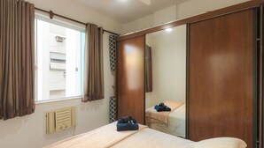 A bedroom with a bed, a wardrobe, a window with curtains, and a wall-mounted air conditioning unit. - 360 Flamengo Marques de Abrantes By SUHCasa (Rio de Janeiro)