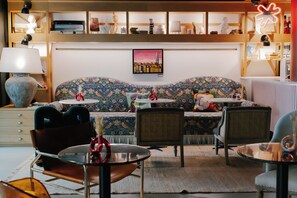 A cozy living room with a patterned sofa, a coffee table, and a bookshelf filled with books and decorative items. - Artcore Hotel Porto (Porto)