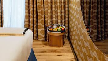 A hotel room with a bed, a small wooden table, and a mirror reflecting the room's decor.