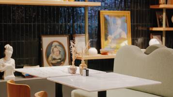 Un intérieur moderne avec un canapé, une table et une chaise. On y trouve des étagères remplies de divers objets et un tableau accroché au mur.