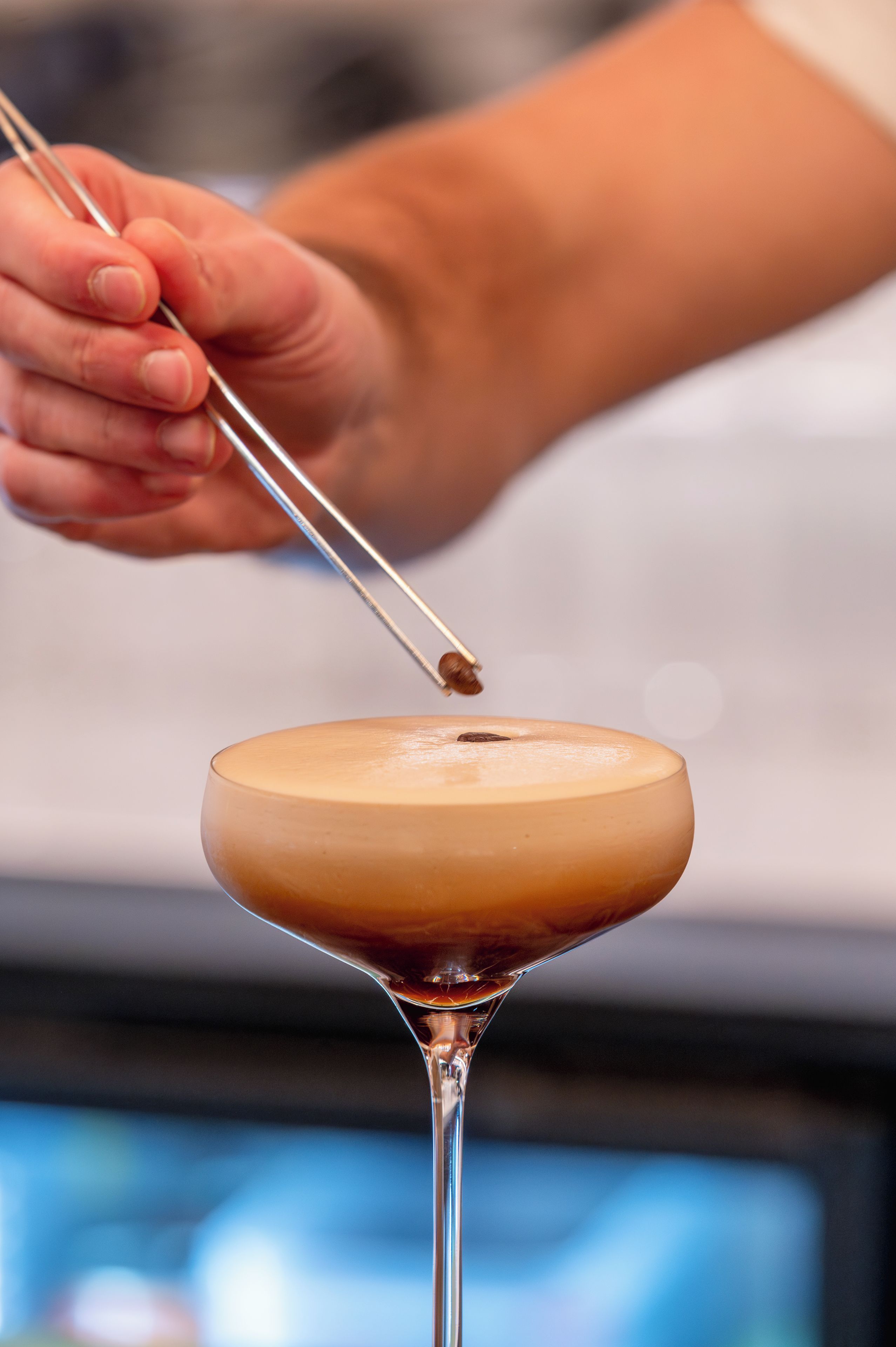 A person using chopsticks to handle a drink in a martini glass.