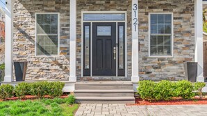 A stone facade with a black front door, two windows with blinds, and a number '3121' above the door. - Elegant Open Concept Close To DC (Arlington)