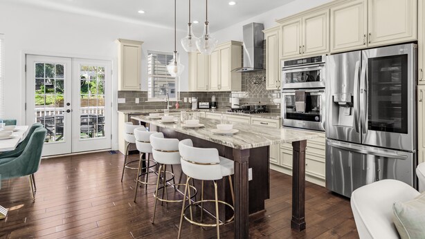 A modern kitchen with a large island, stainless steel appliances, and a dining area with bar stools. - Elegant Open Concept Close To DC (Arlington)