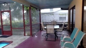 A covered outdoor area with a table and chairs, a small pool, and a glass door leading outside. - The Palms at Poinciana: Private Tropical Resort (Kissimmee)