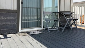 A covered outdoor area with a sliding glass door, a small table, and a bench.