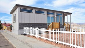A modern, single-story building with a white picket fence, large windows, and a wooden deck.